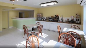 Una cocina luminosa con armarios blancos, un comedor con sillas de madera y un ventilador de techo.