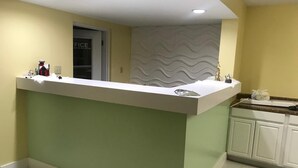 Una cocina con encimera blanca, armarios verdes y un salpicadero con diseño.