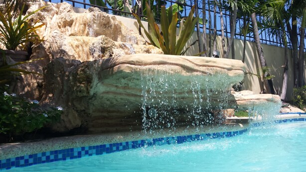 A pool with a rock formation and water cascading over it. - Kim Beatriz Compound (Lapu-Lapu)