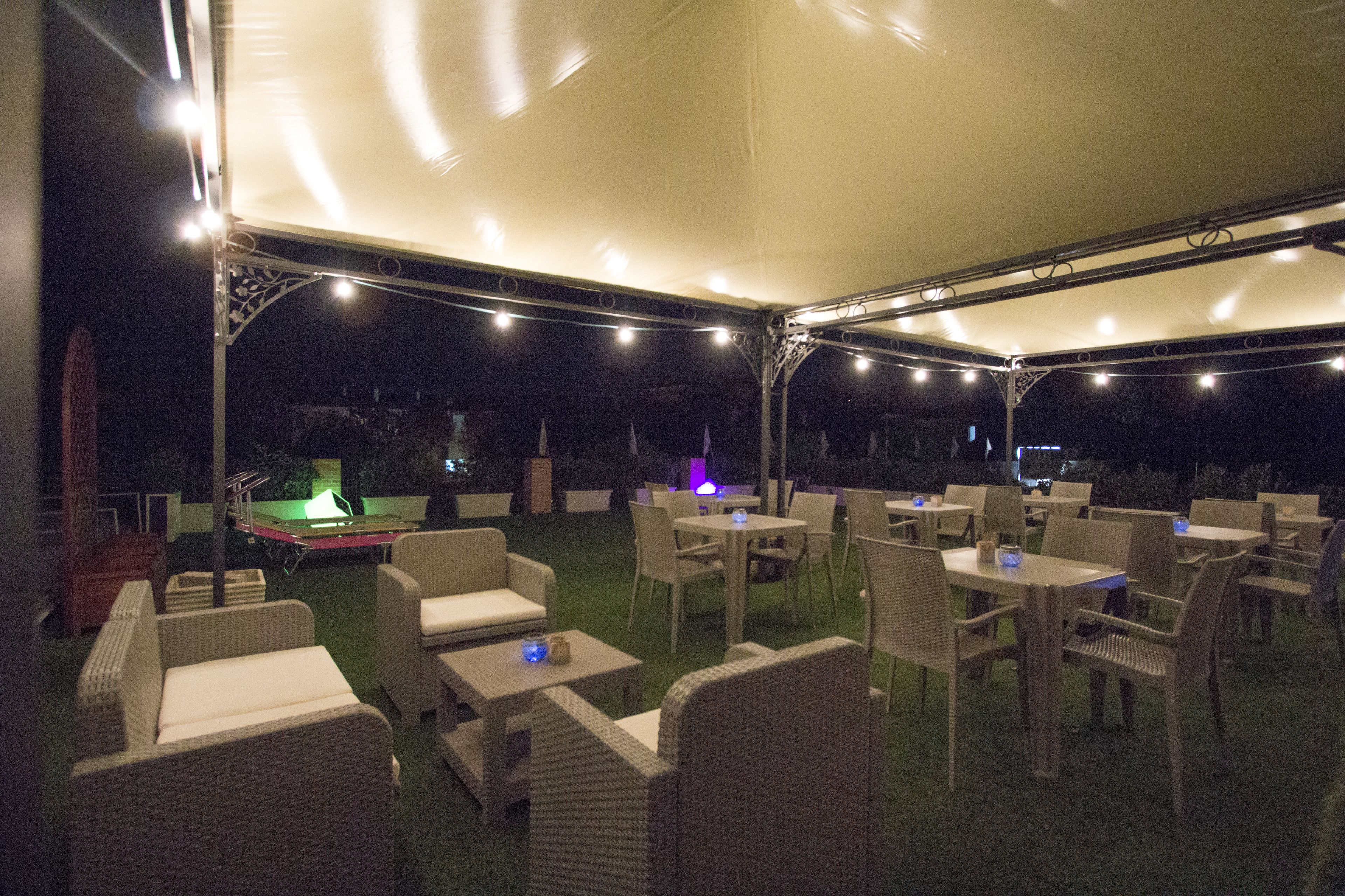 An outdoor patio with wicker furniture and string lights.