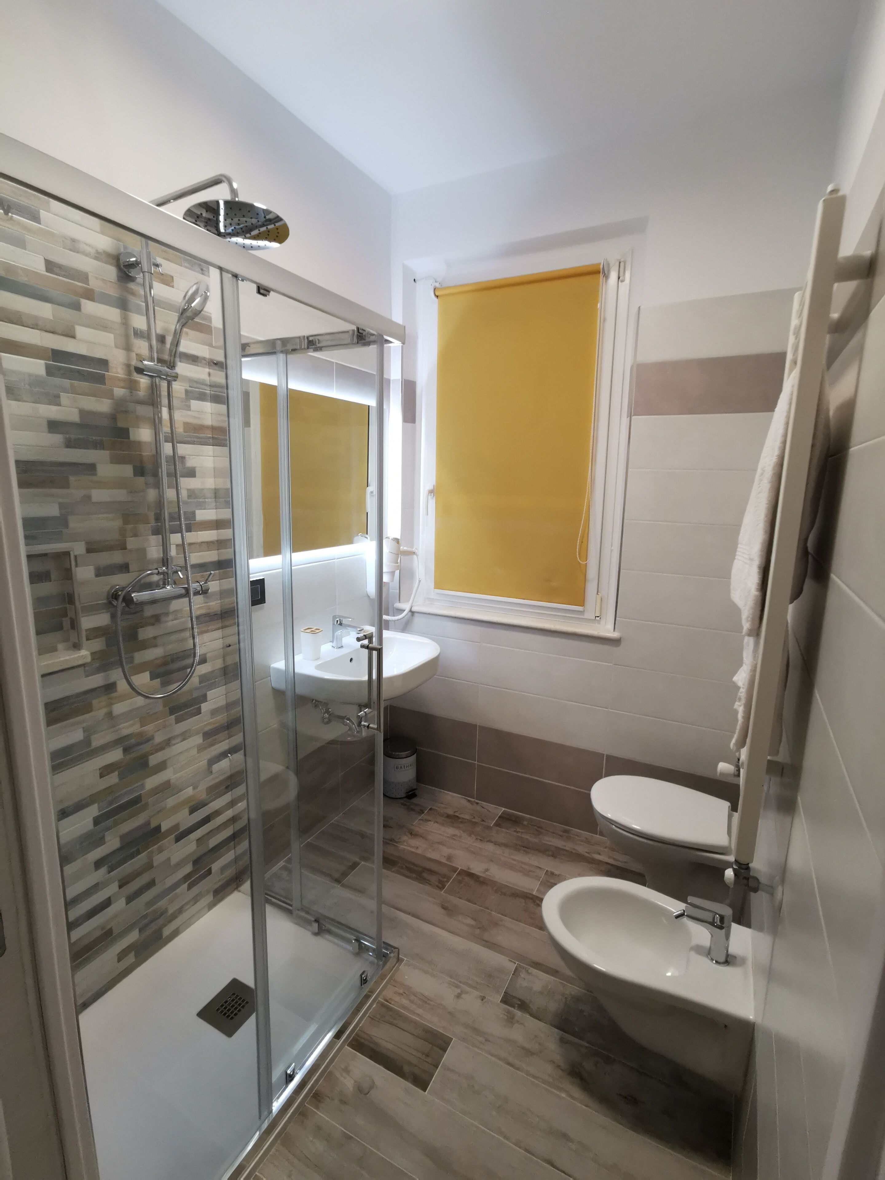 Un baño moderno con ducha envuelta en vidrio, un lavabo blanco y un inodoro.