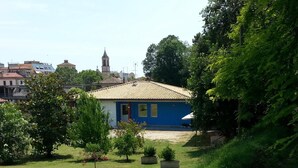 Un pequeño edificio azul con tejado de tejas, rodeado de vegetación y árboles.