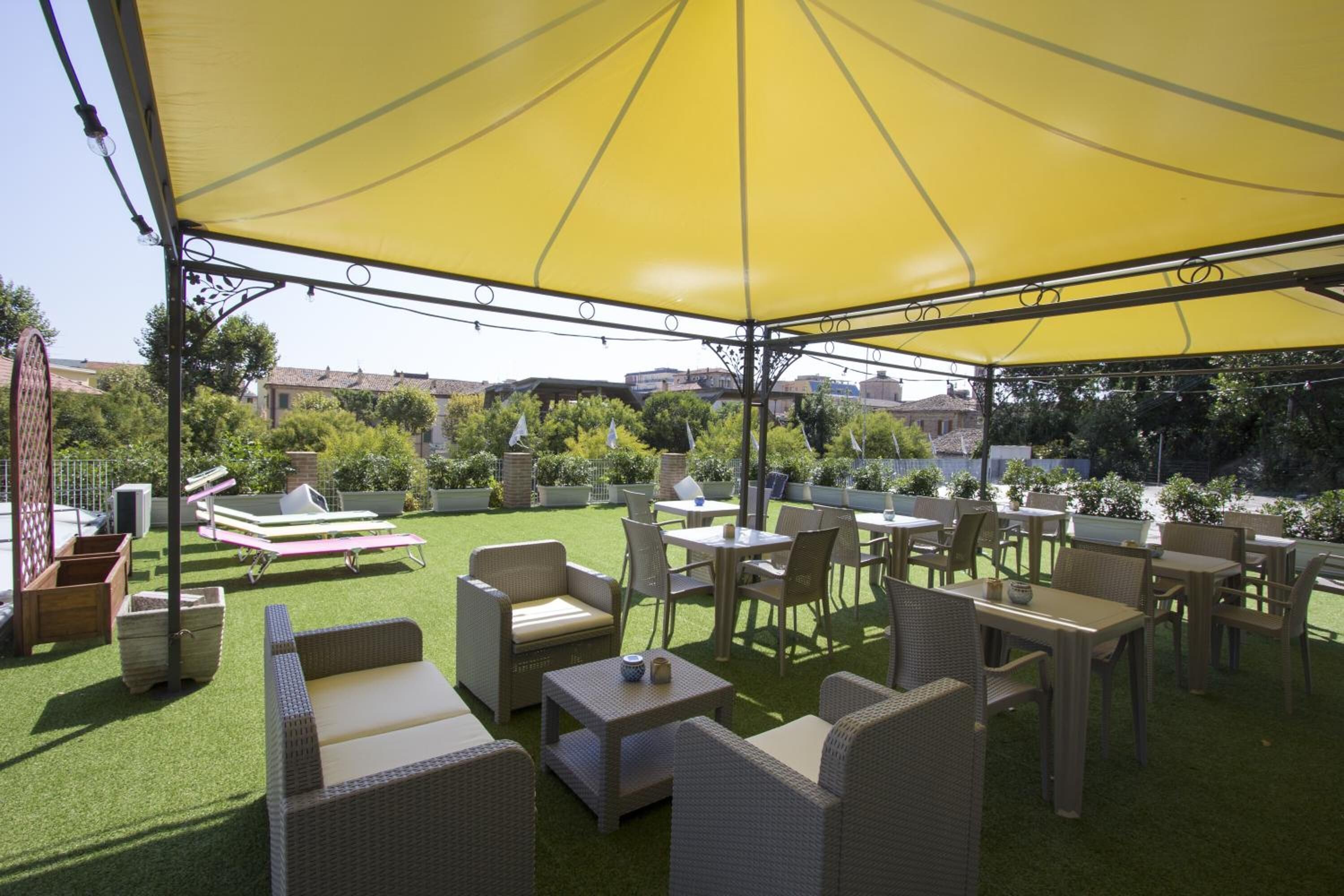 Un patio al aire libre con mobiliario de mimbre, un toldo amarillo y vistas del vecindario.