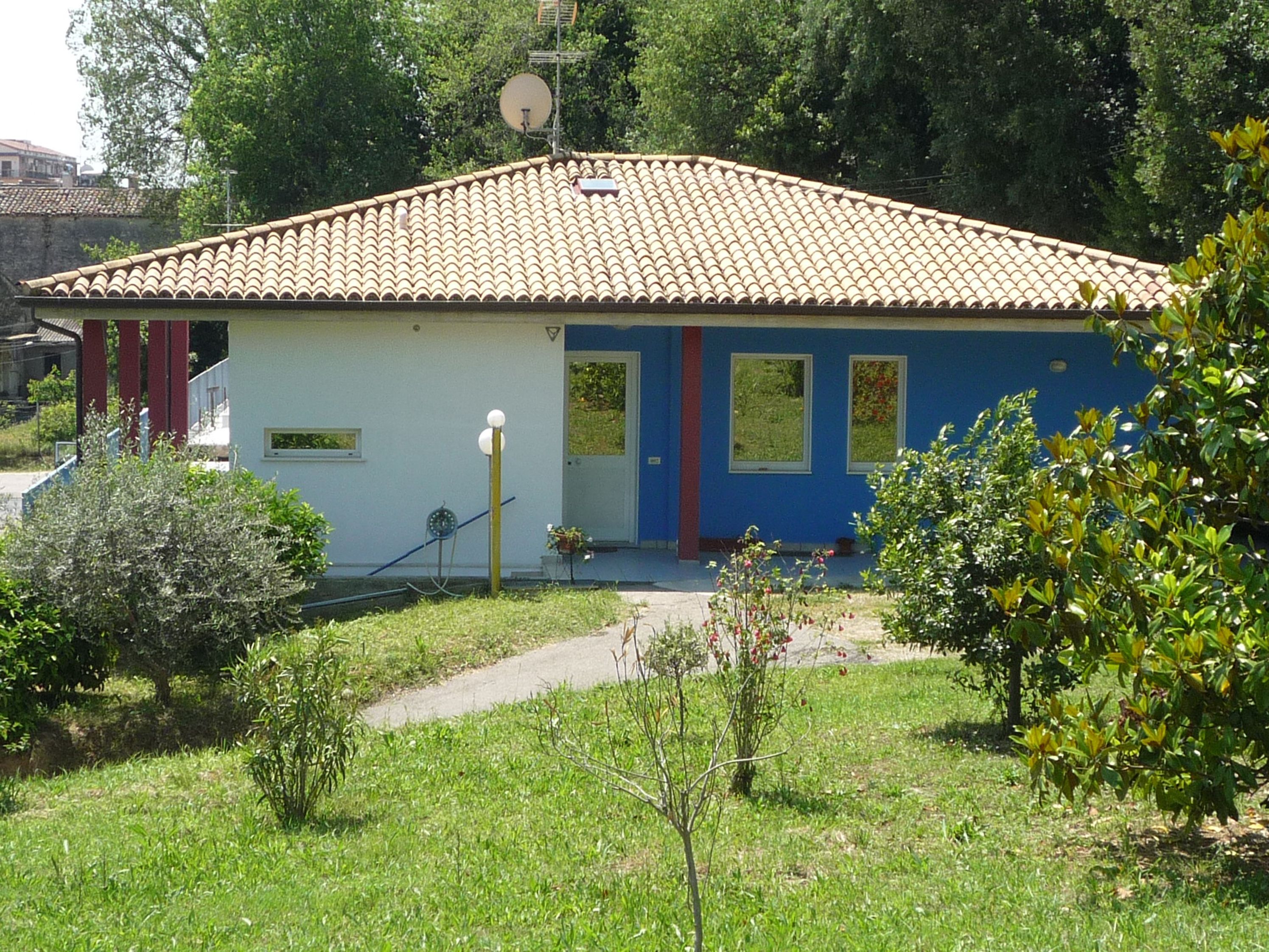 A single-story house with a tiled roof, a small porch, and a garden in front.