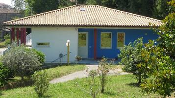 A single-story house with a tiled roof, a small porch, and a garden in front.