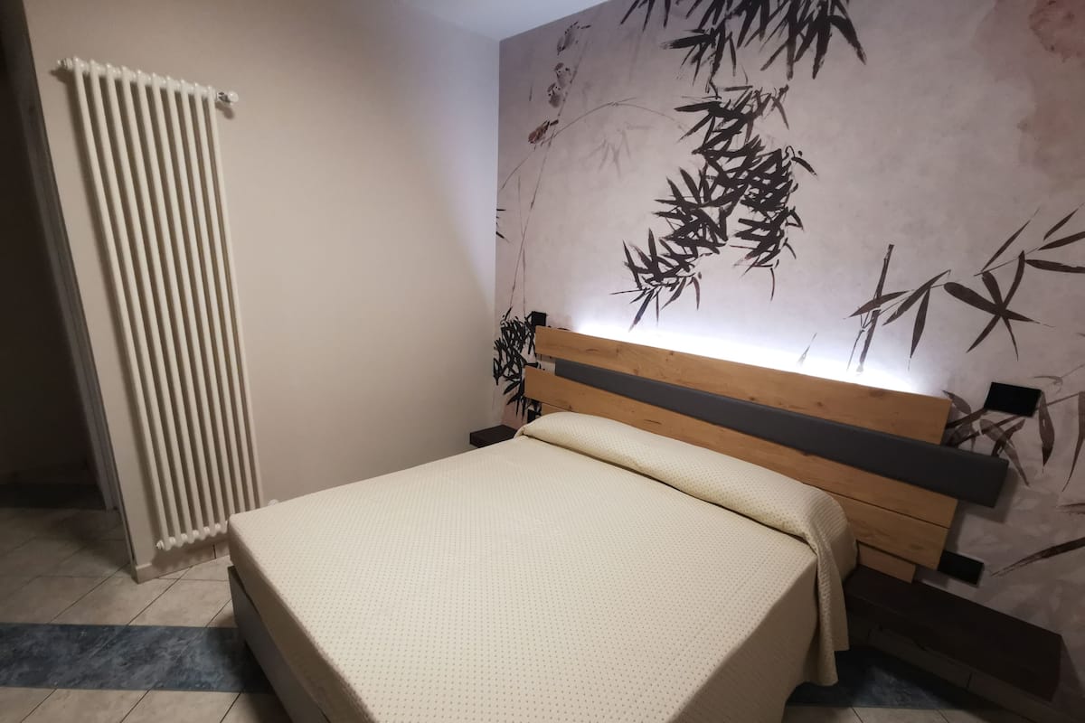 Una camera da letto con un letto, un termosifone e una parete decorata con elementi in bambù.