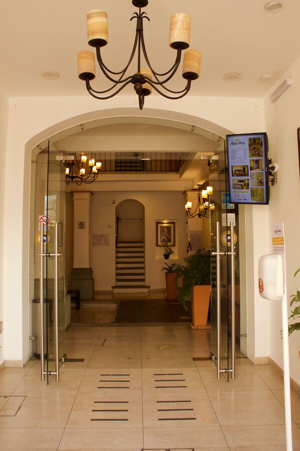 A hotel lobby with a chandelier, a staircase, and a reception area. - Hotel Real Alma  (Oaxaca)
