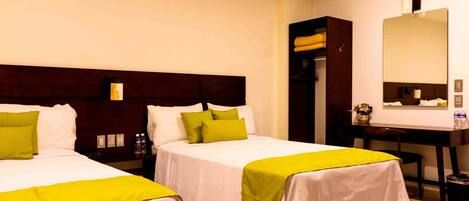 A hotel room with two beds, a desk, a chair, a mirror, and a wardrobe.