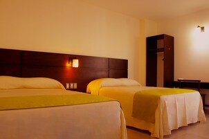 Una habitación de hotel con dos camas, un armario y una mesita de noche con lámpara.
