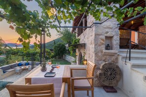 An outdoor seating area with a table and chairs, surrounded by stone walls and greenery. - NINON - Design B&B - Adults Only (Dubrovnik)