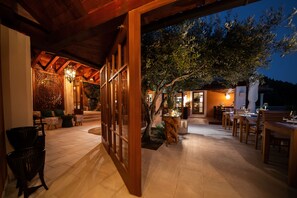 An outdoor patio area with wooden furniture, a dining table, and a large tree. - NINON - Design B&B - Adults Only (Dubrovnik)