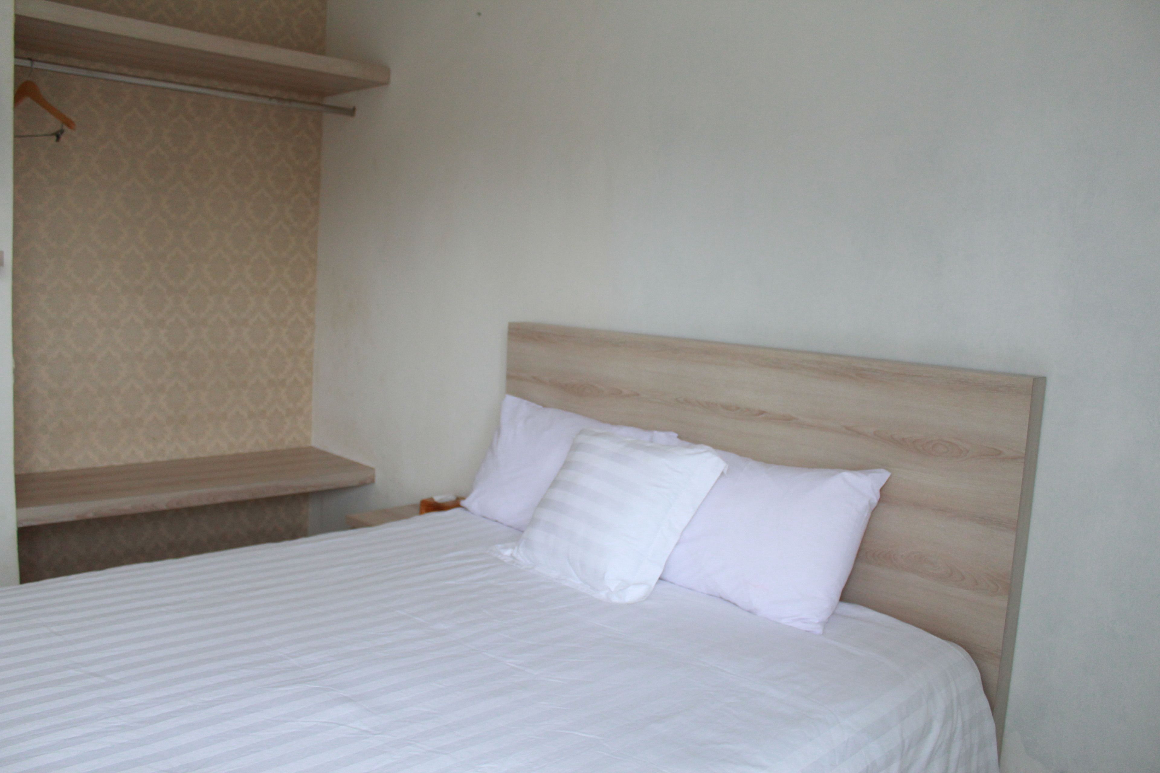 Una cama bien hecha con cabecera de madera y ropa de cama blanca.