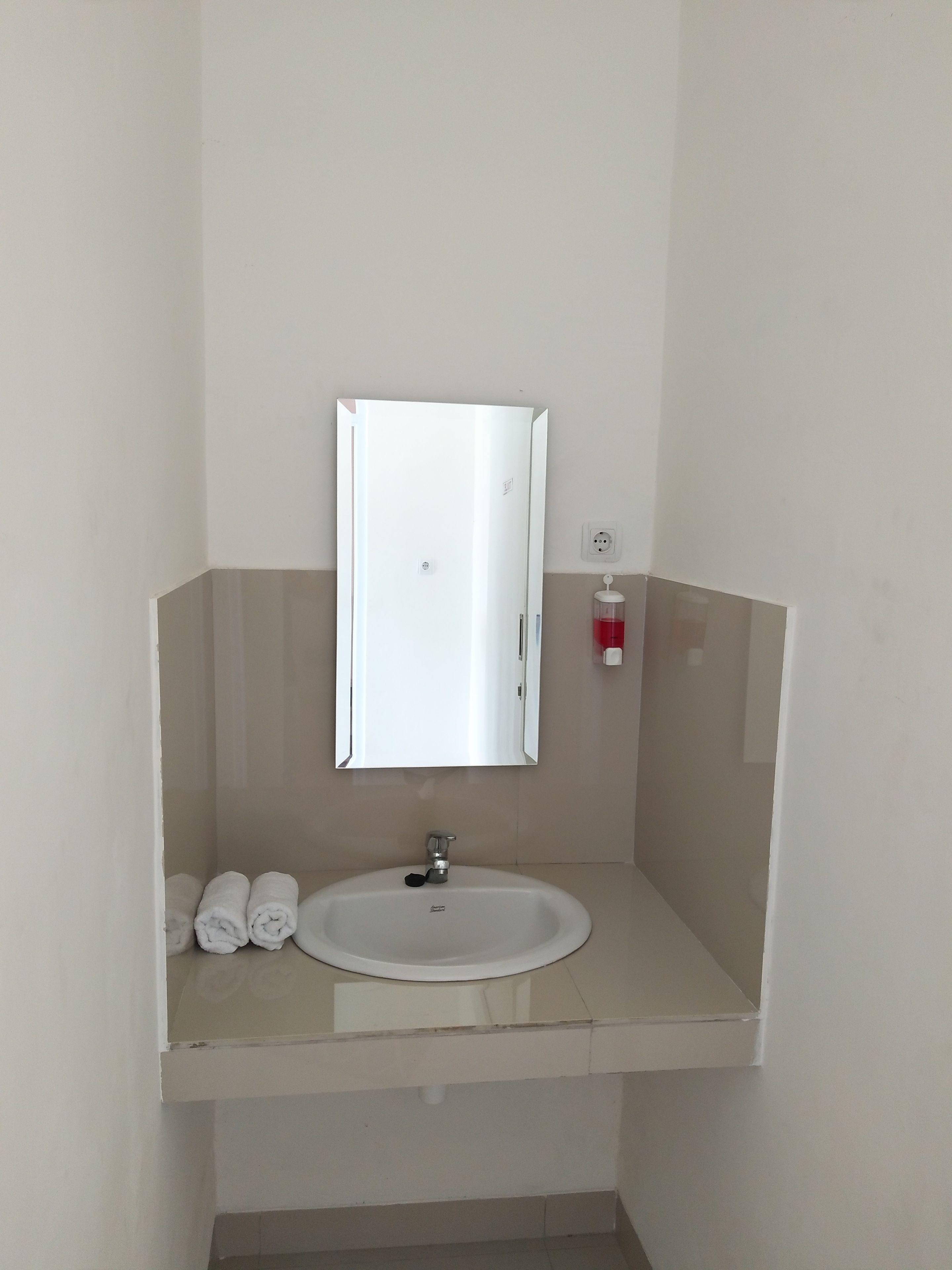 A bathroom with a white sink, a mirror, and a towel rack.