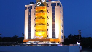 Un hotel de varios pisos con un llamativo letrero de neón que dice "HOTEL Jin".