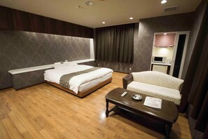 A hotel room with a large bed, a sofa, a coffee table, and a microwave in the corner. - Hotel JIN (Adult Only) (Hamamatsu)