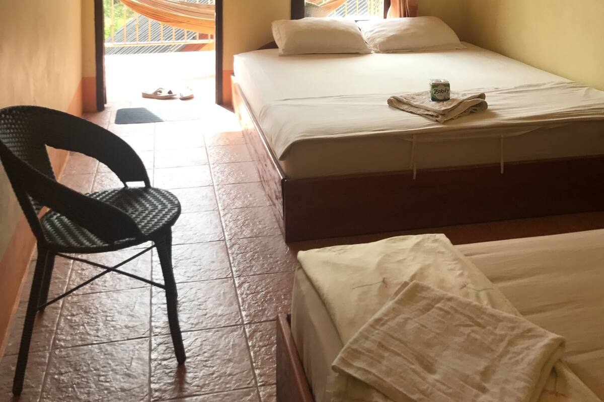 Un dormitorio con una cama, una silla y vistas a un balcón con una hamaca.