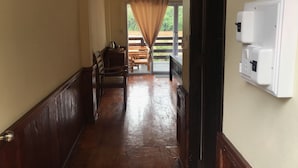 Een hal met houten banken, een houten tafel en uitzicht op een terras.