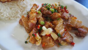 Un plato de panceta de cerdo frita con arroz y un huevo frito.