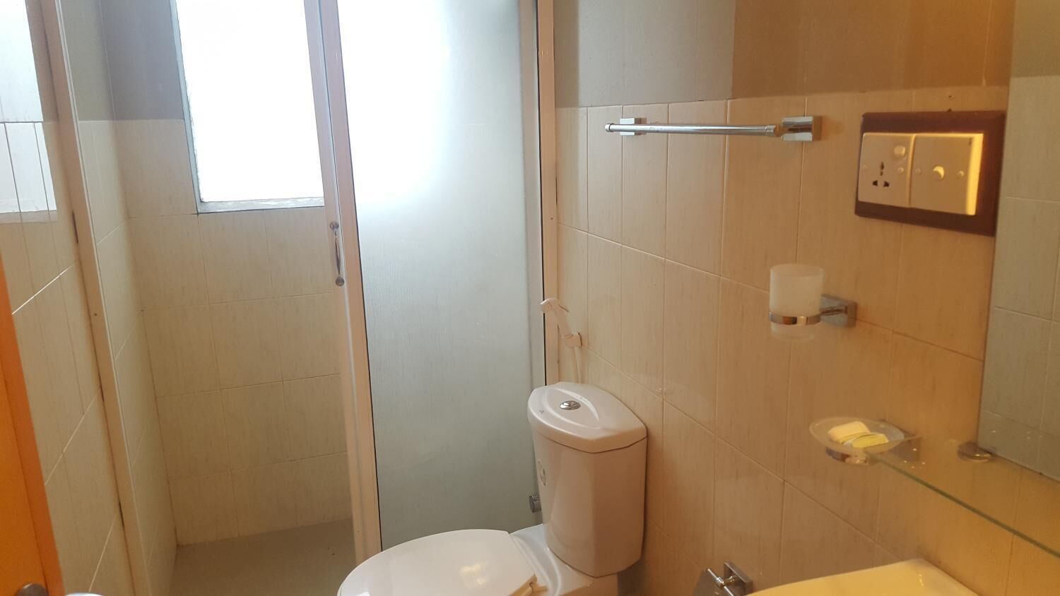 Un baño con inodoro, cabina de ducha de vidrio, toallero y espejo.