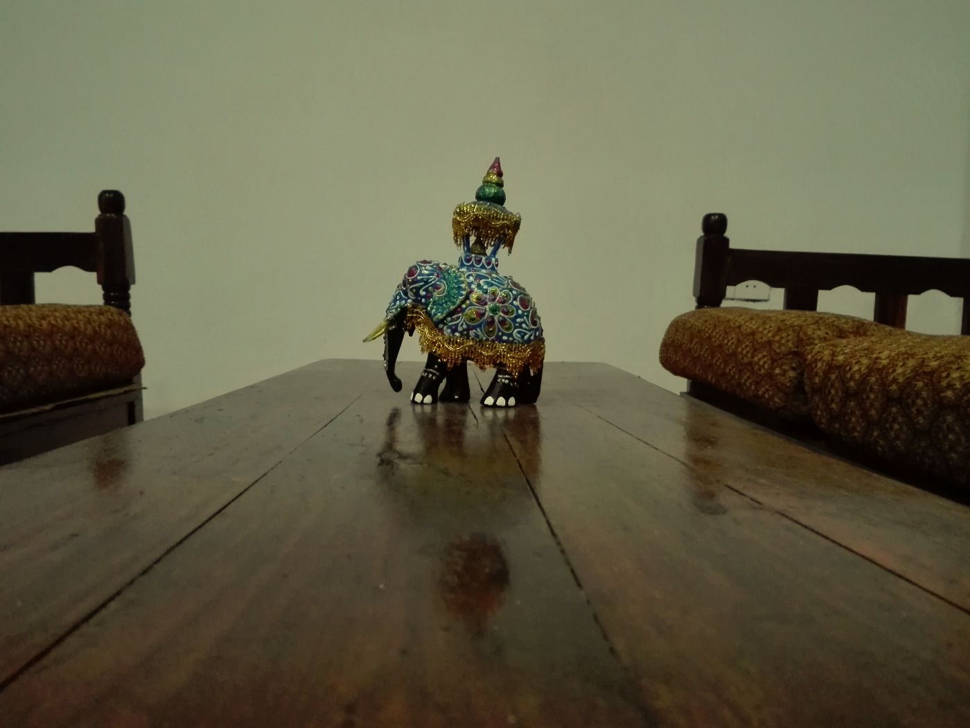 A wooden dining table with a decorative elephant figurine in the center.
