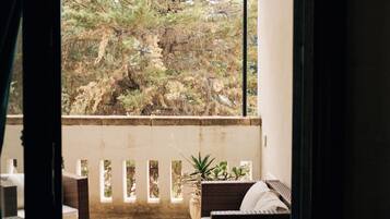 A balcony with wicker furniture, a small table, and a potted plant.