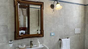 Ein Badezimmer mit großem Spiegel, Waschbecken, Handtuchhalter und einer Wandleuchte.