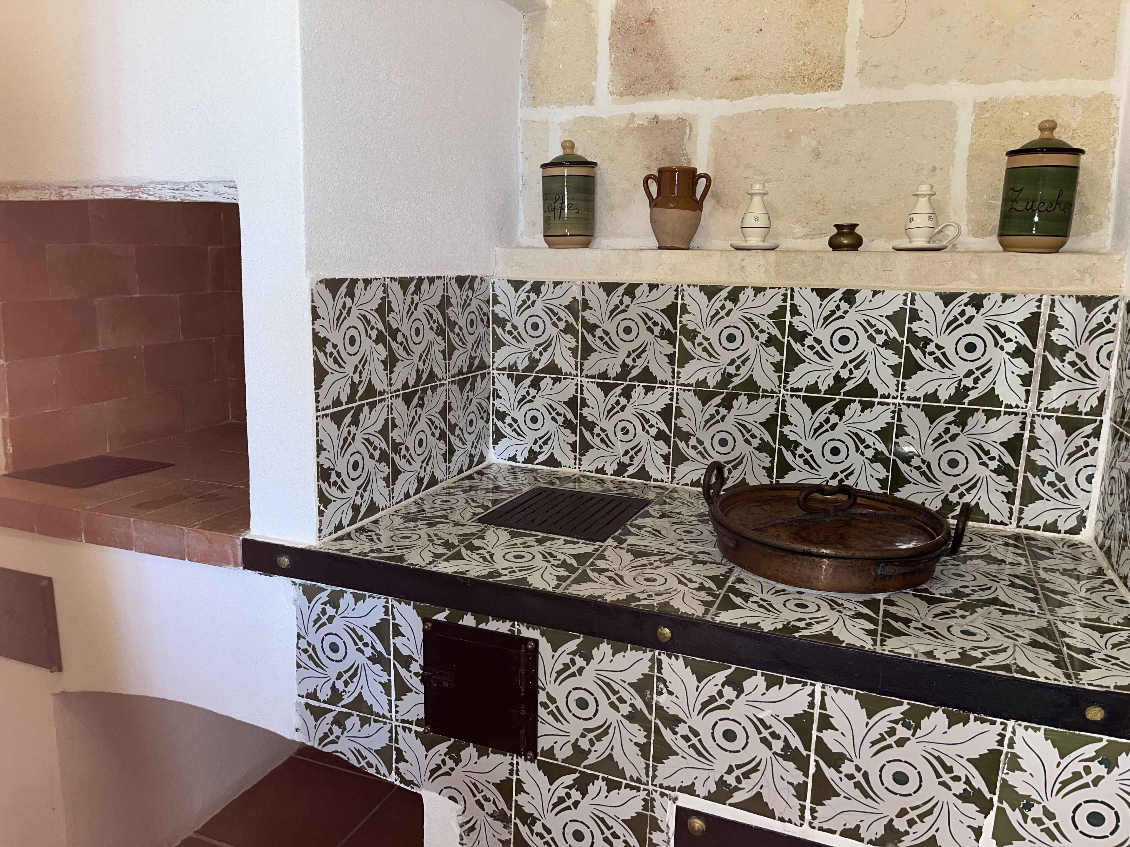 A kitchen with patterned tiles, a black countertop, and a brick wall.