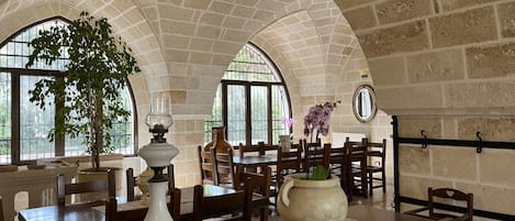 A dining area with arched brick ceilings, wooden tables, and chairs.