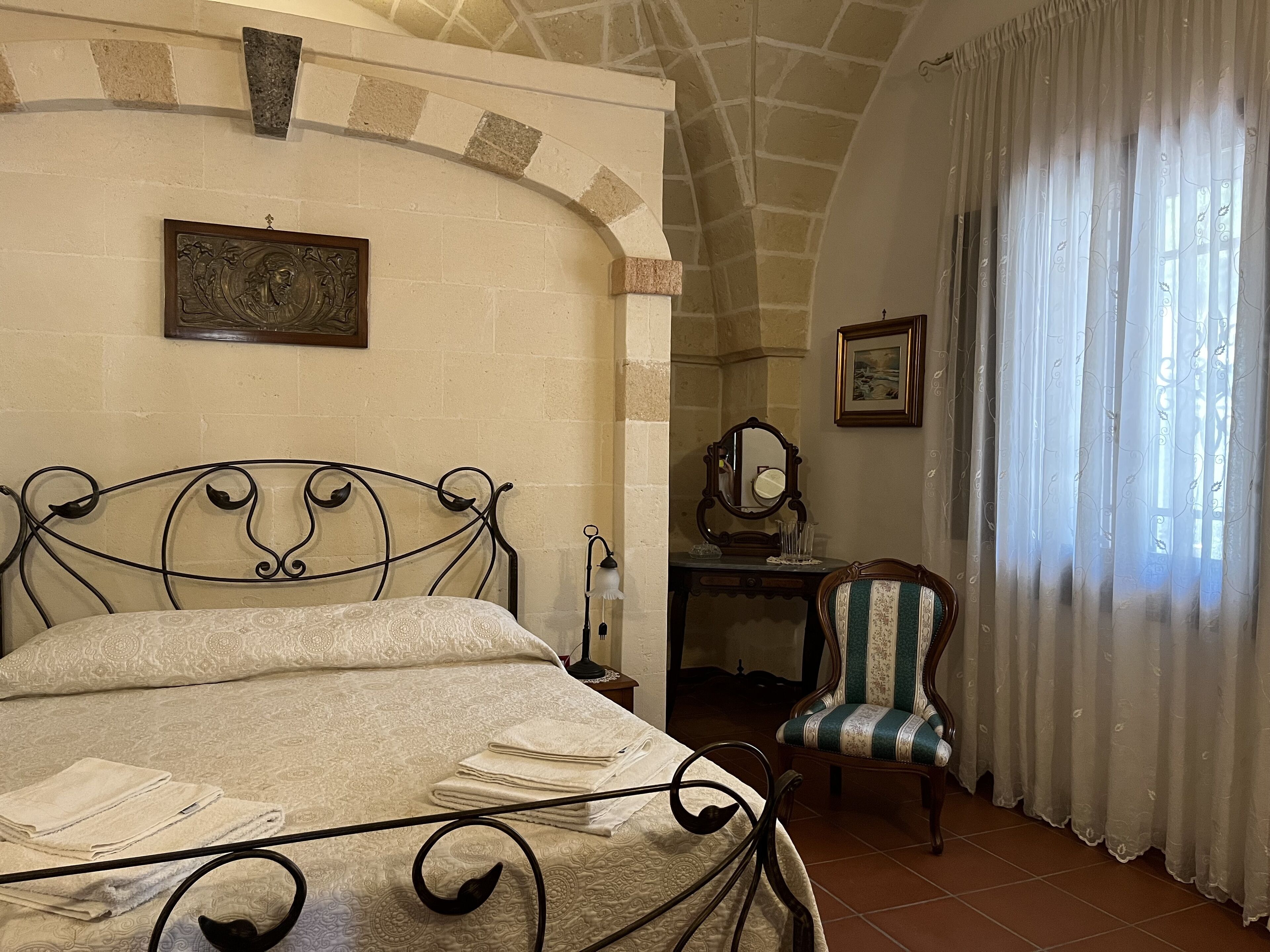 A bedroom with a bed, a desk, a chair, and a window with curtains.