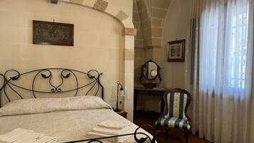 A bedroom with a bed, a desk, a chair, and a window with curtains.