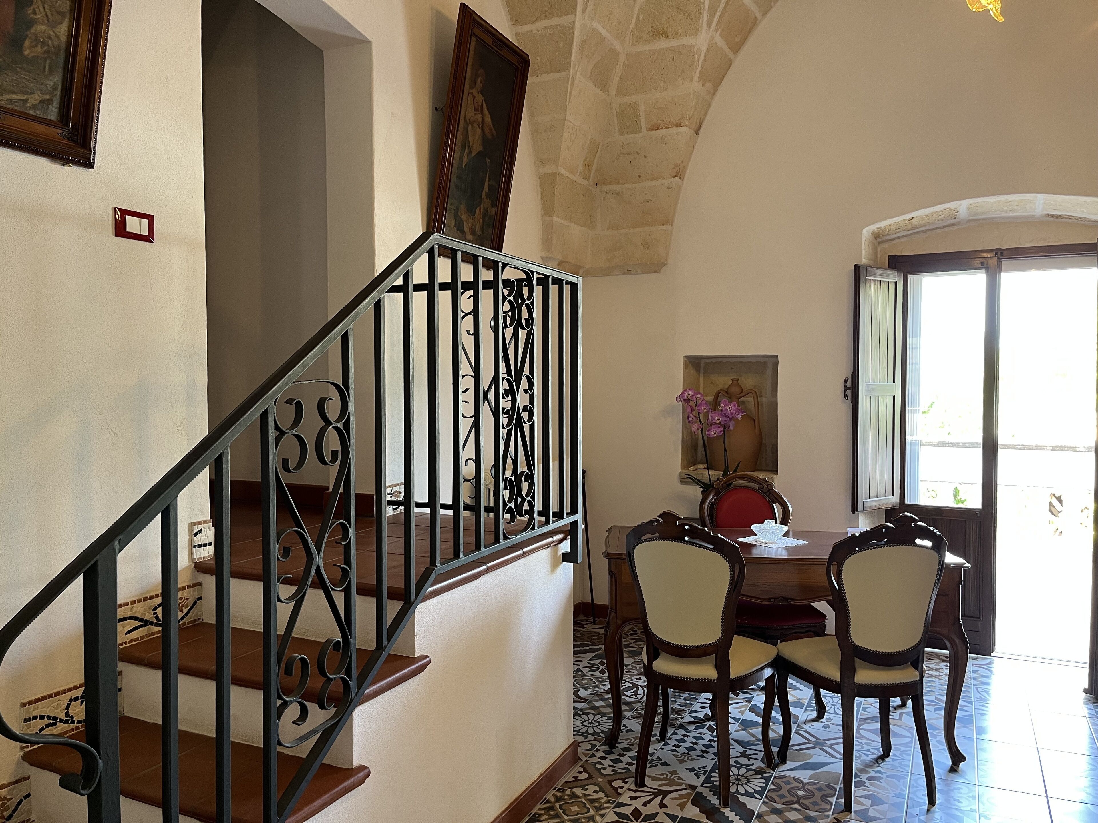 Un escalier orné de rampes en métal menant à une salle à manger avec une table et des chaises.