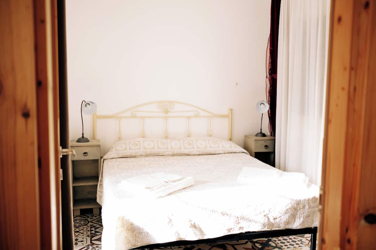 A bedroom with a bed, two bedside tables, a nightstand, and a patterned floor.