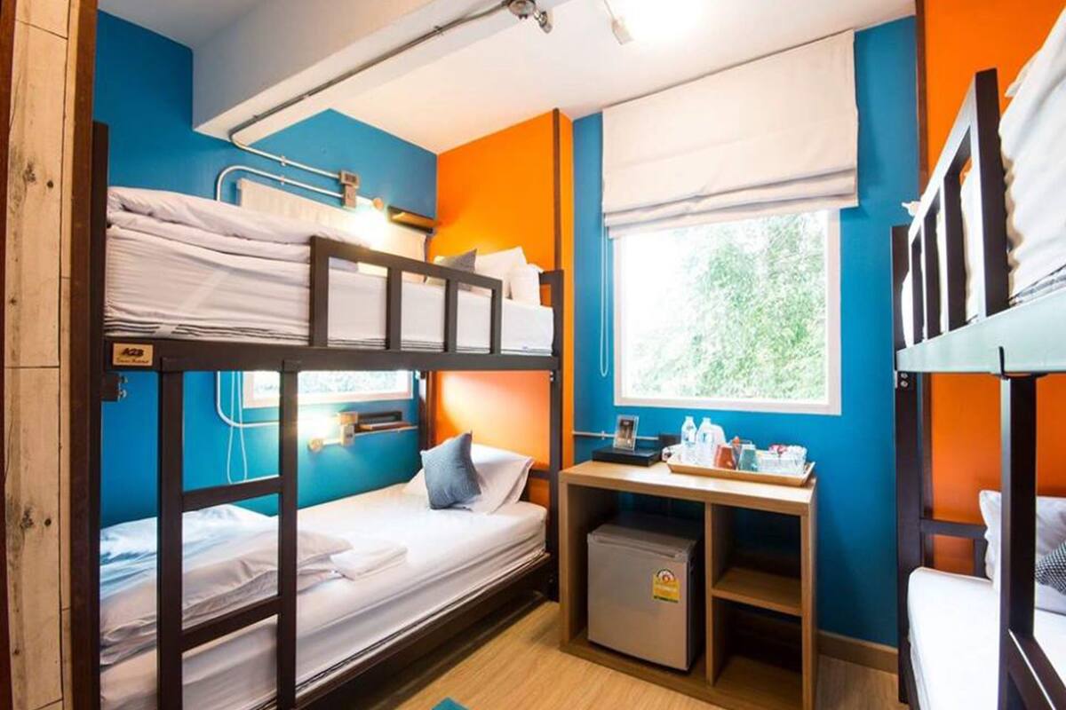 A bunk bed room with a desk and a small refrigerator.
