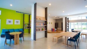A modern library with a green wall, wooden tables, and blue chairs. - Pattaya Sea View Sandstorm (Pattaya)