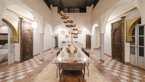 A spacious dining area with a long table, arched doorways, and a checkered floor. - Dar Tafantant (Ourika)