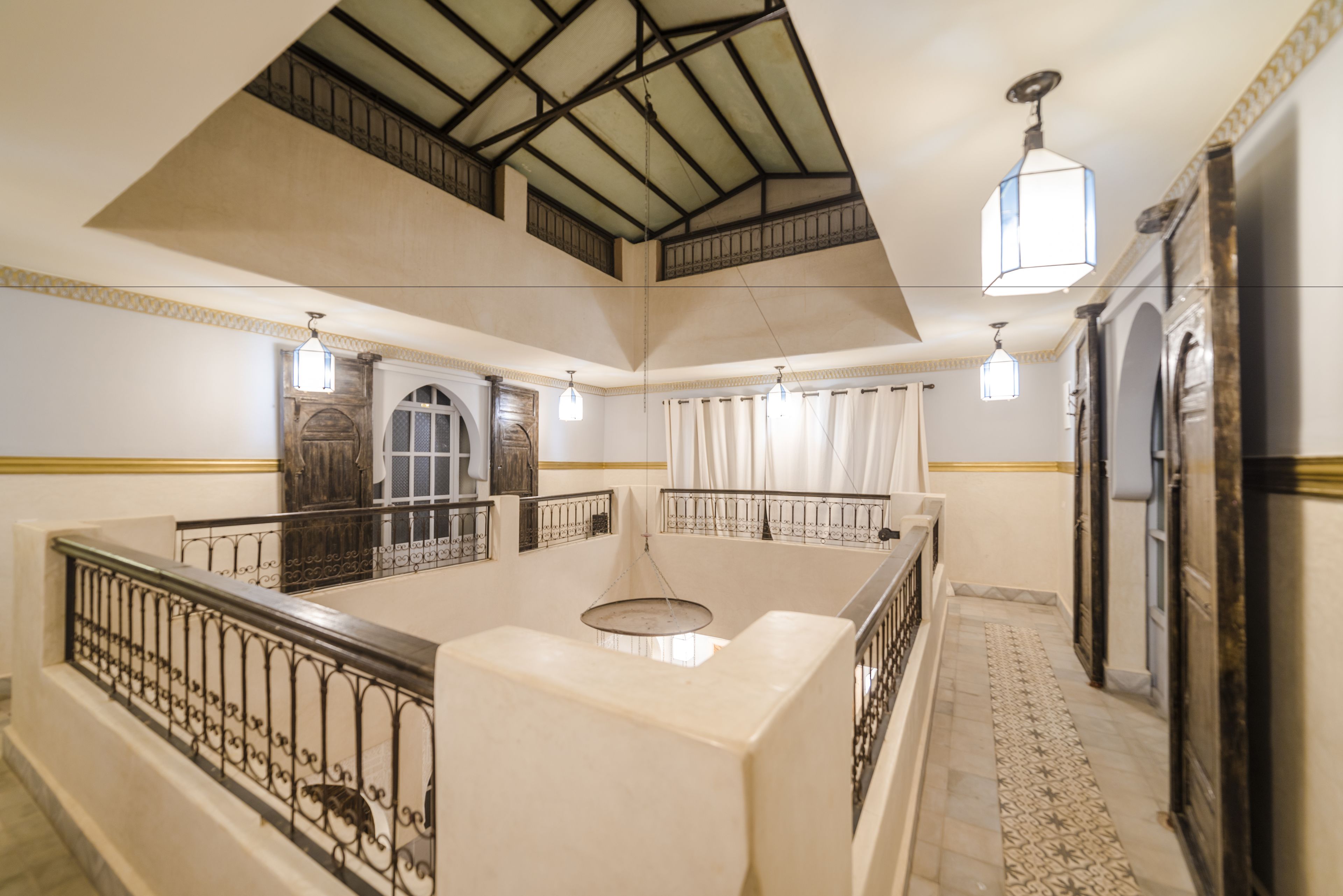 A spacious interior with a high ceiling, a central open area, and a staircase leading to an upper level.