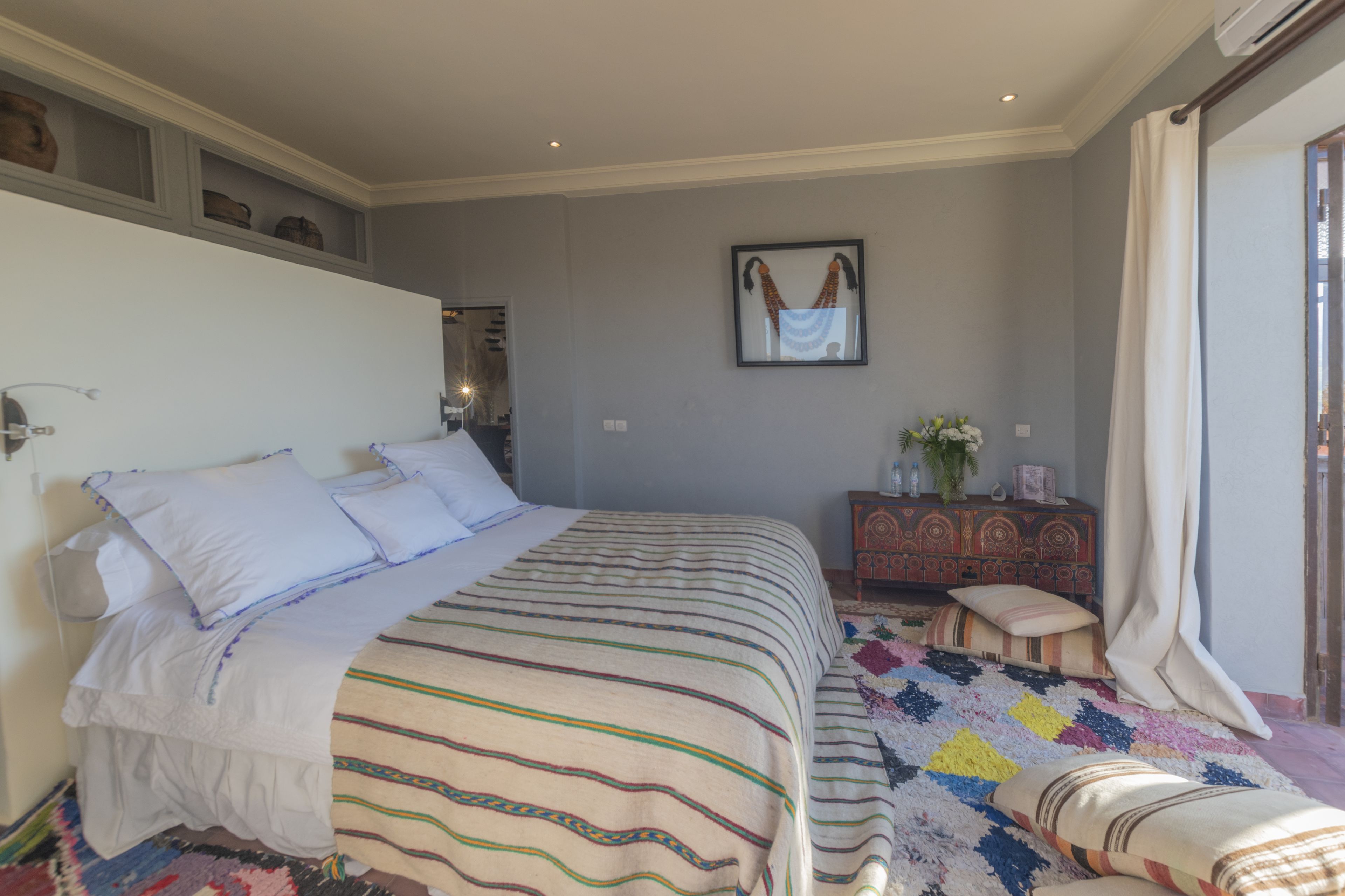 Een slaapkamer met een groot bed, een dressoir en een raam met gordijnen.