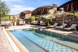 Una piscina al aire libre, sombrillas, sillones reclinables de piscina