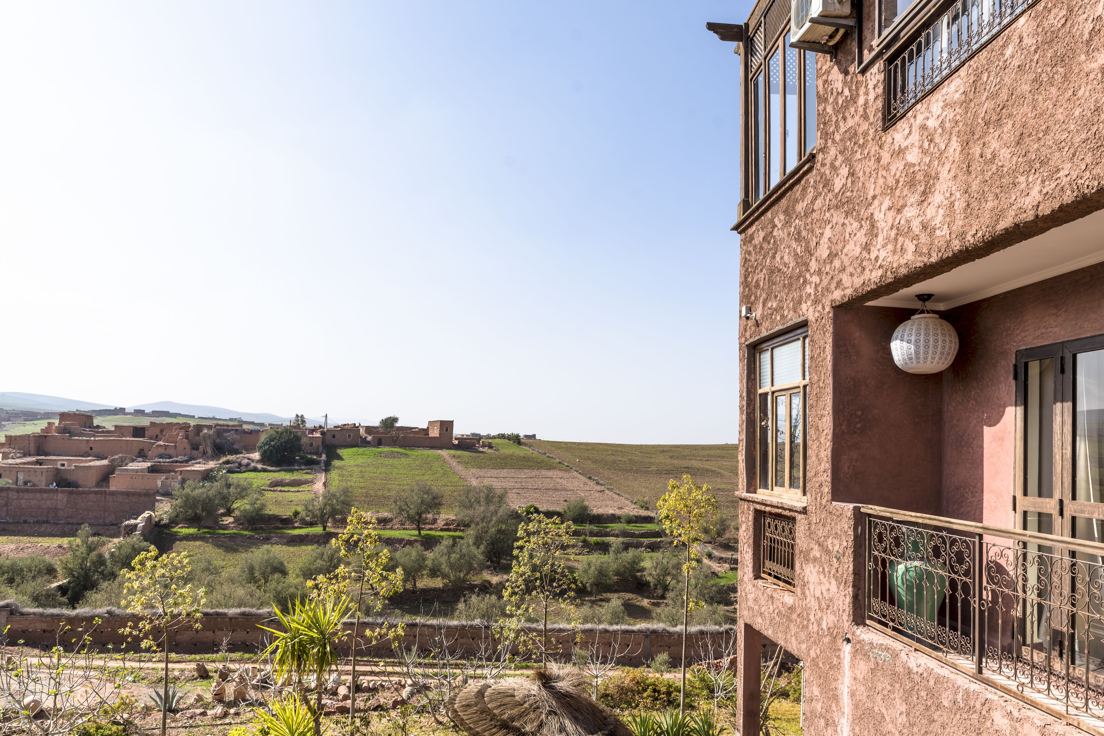 Een gebouw met een balkon, met uitzicht op een landelijk landschap met velden en een kasteel in de verte.