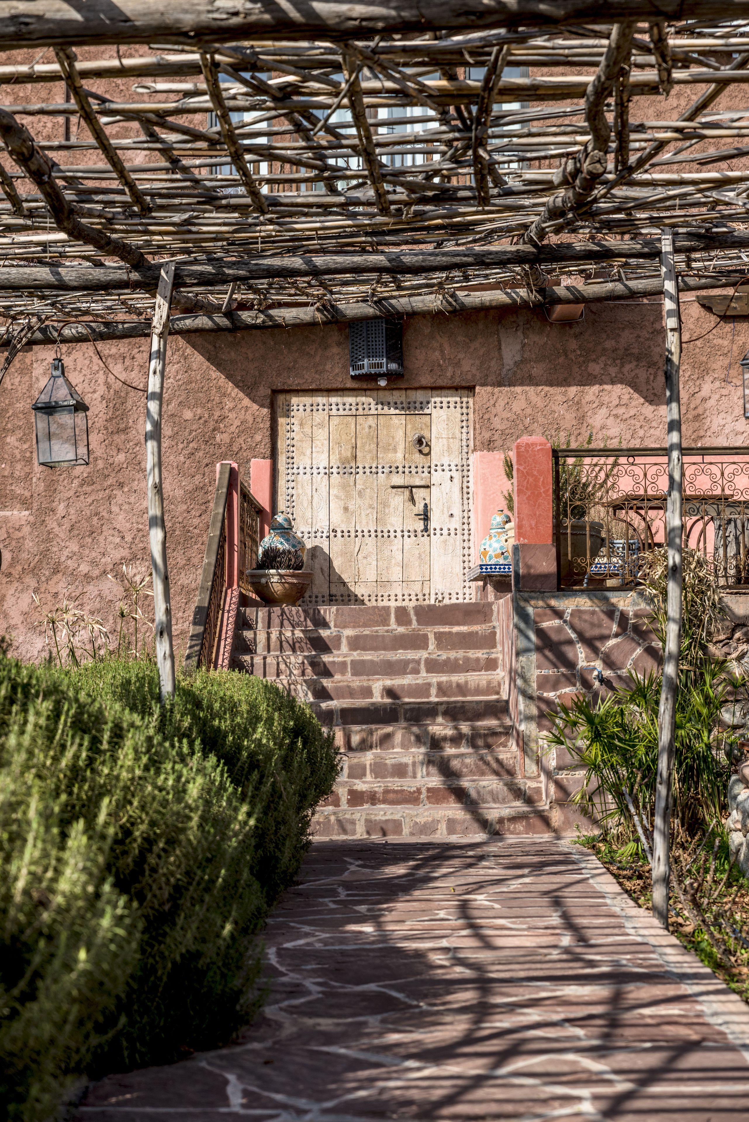 Un sendero de piedra que conduce a un edificio con una puerta de madera y un portón de metal.
