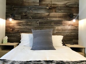 A bedroom with a wooden headboard, two bedside lamps, a white bedspread, and a gray pillow. - Purple Mountain Bed & Breakfast (Crested Butte)