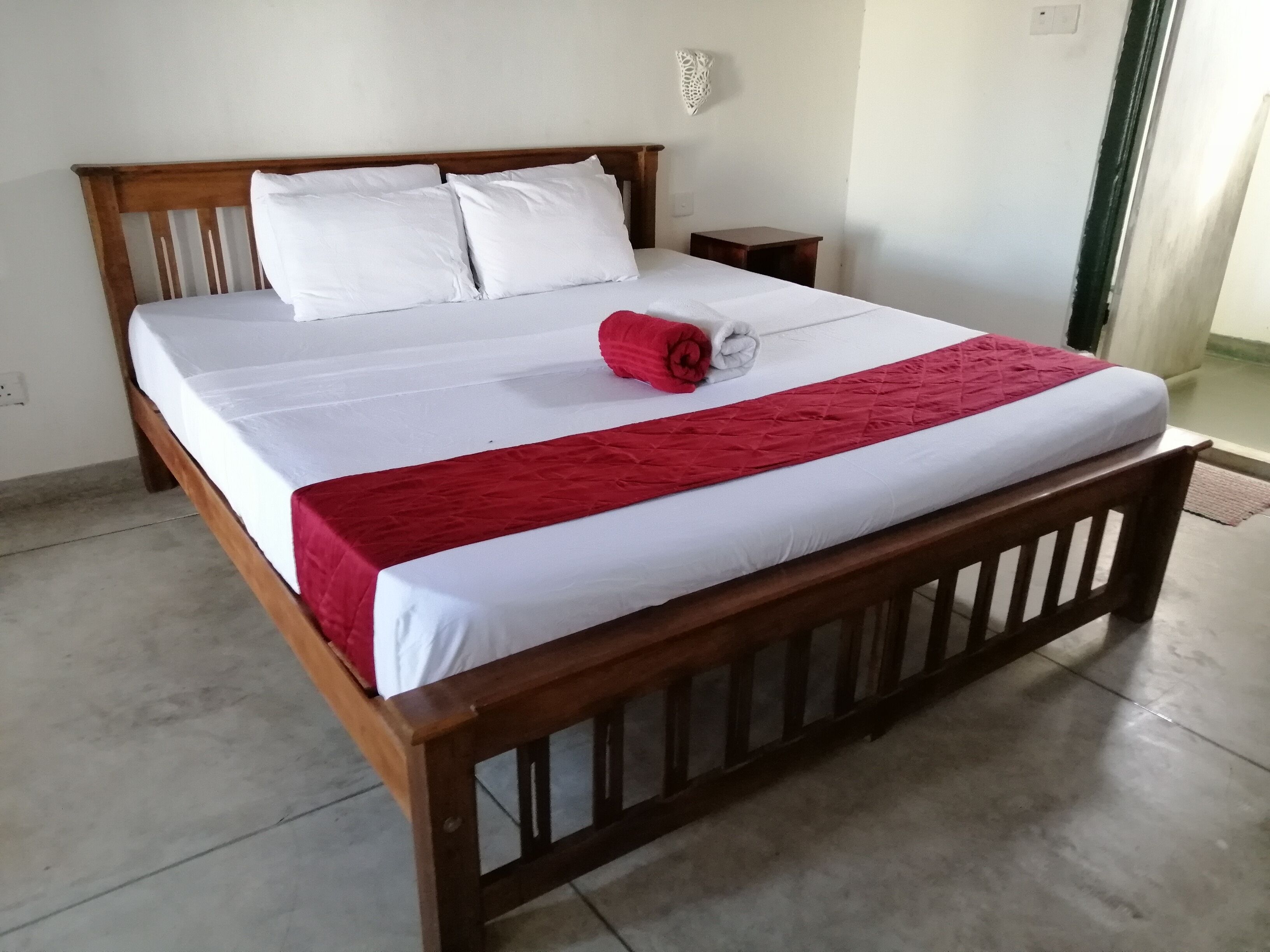 Cama bem arrumada com lençóis brancos e detalhes vermelhos.