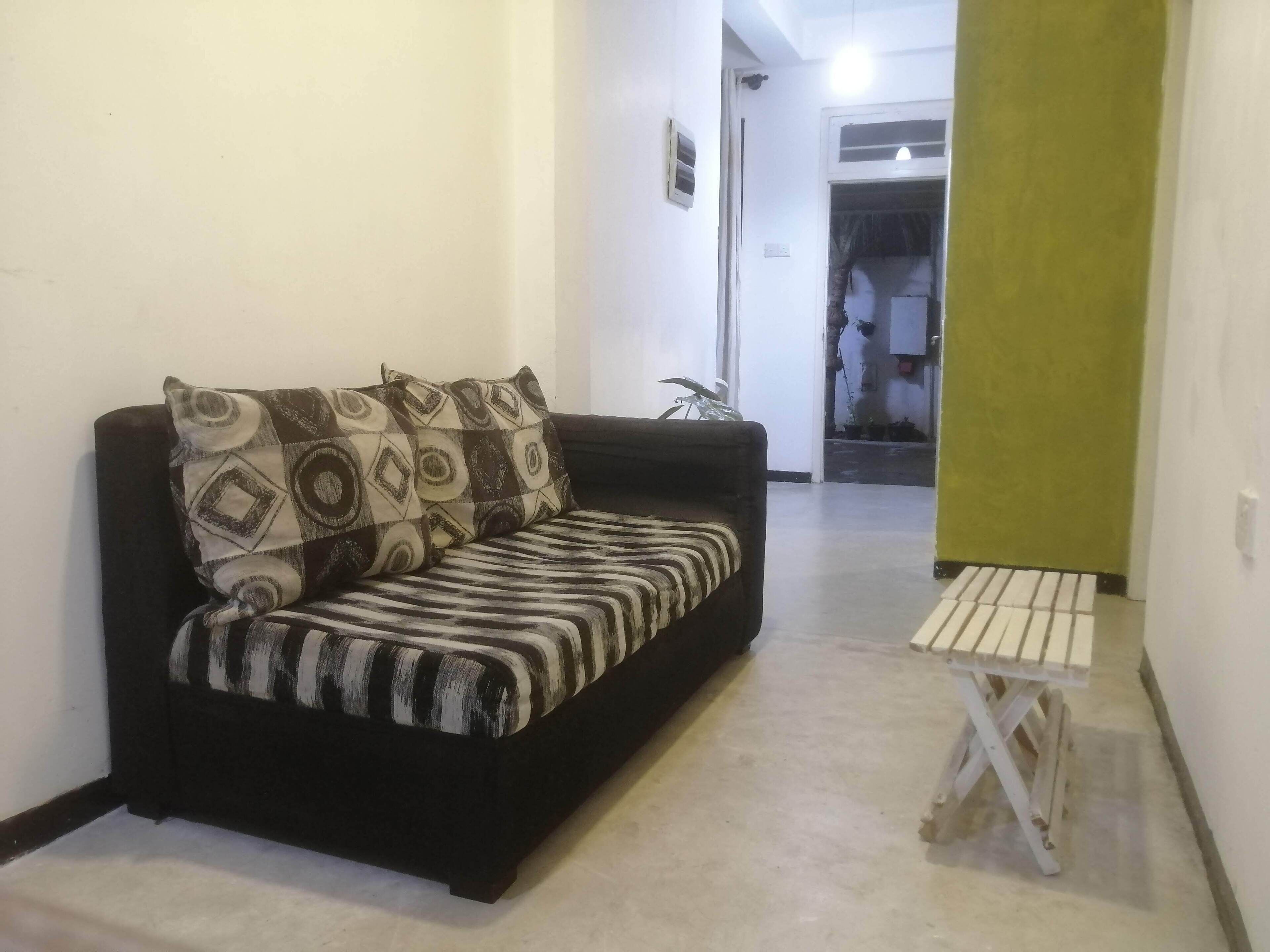 A living room with a sofa, a small table, and a green wall.