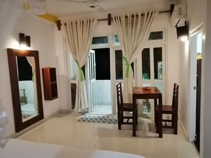 Une chambre d’hôtel avec un coin repas, un grand miroir, une petite table avec des chaises et une vue sur l’extérieur.