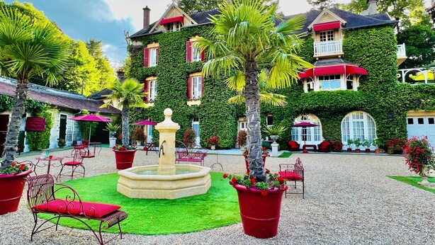 A courtyard with a fountain, red chairs, and potted plants. - Manoir des Cavaliers - BnB (Vineuil-Saint-Firmin)