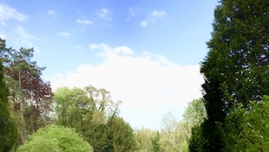 A well-maintained garden with a gravel path, neatly trimmed hedges, and a swimming pool. - Manoir des Cavaliers - BnB (Vineuil-Saint-Firmin)