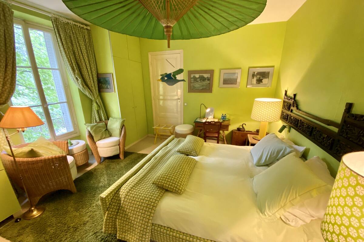 A room with a bed, a desk, a chair, a lamp, and a window with curtains.
