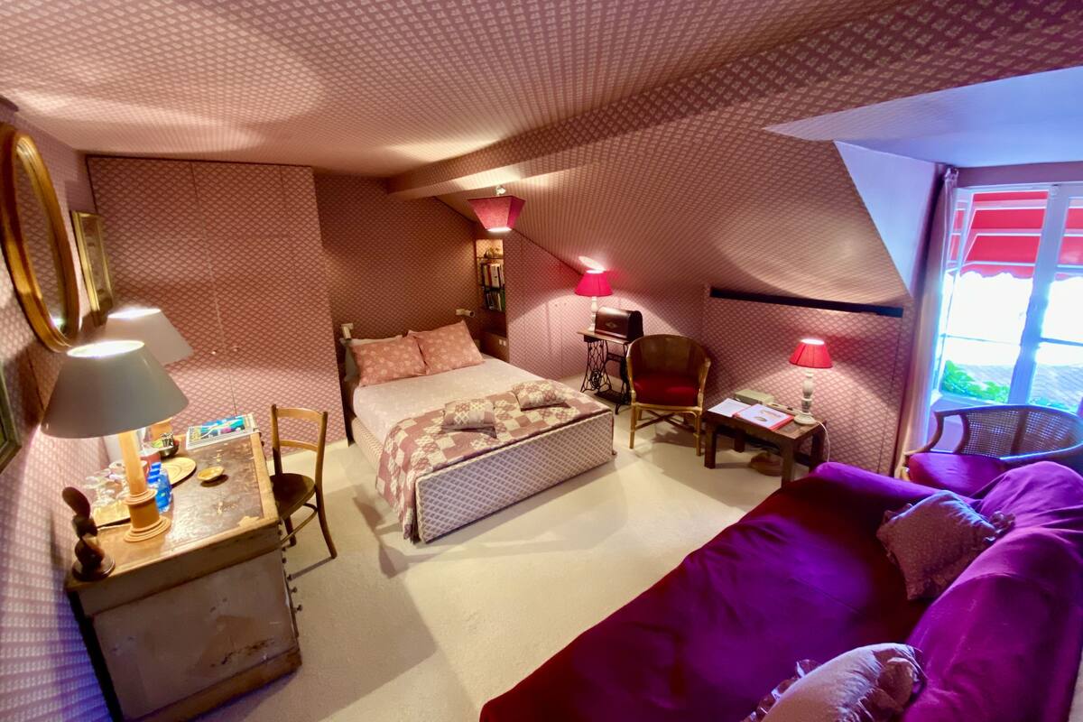 A cozy bedroom with a bed, a desk, a chair, and a couch.