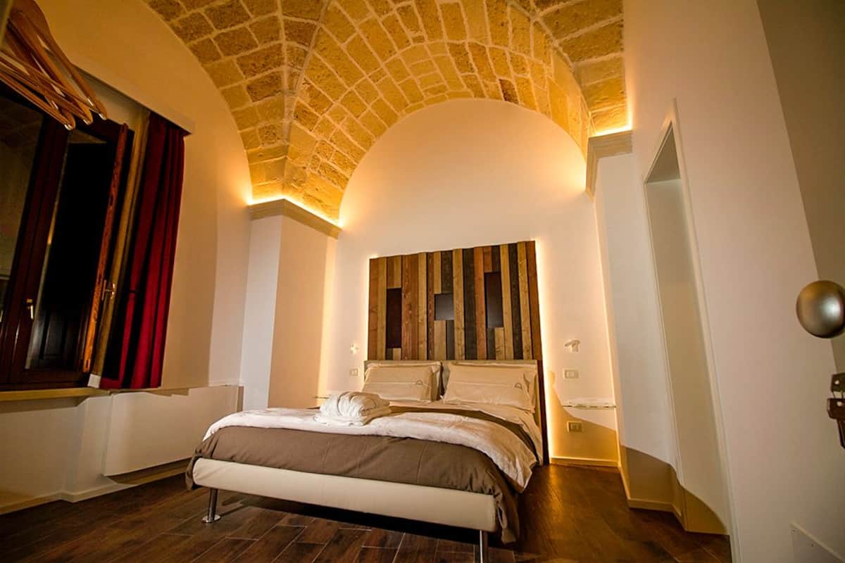 A bedroom with a large bed, a wooden headboard, and a curved ceiling.
