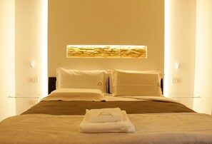 Una habitación de hotel con una cama, una mesita de vidrio y una obra de arte colgada en la pared.